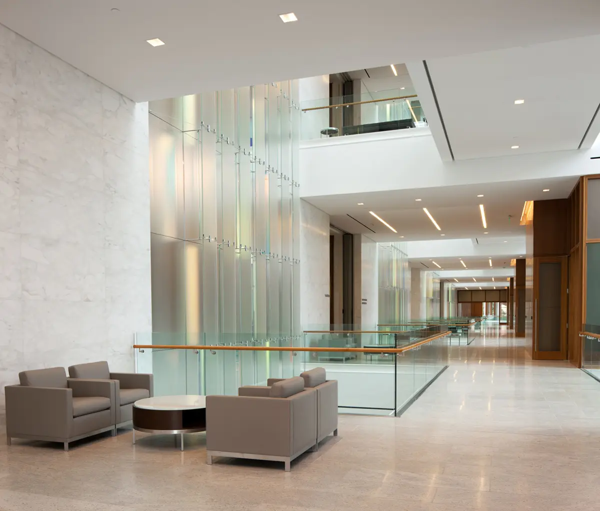 Modern lobby with sleek design features glass walls and minimalistic decor. Neutral-toned seating area conveys a calm, sophisticated atmosphere.