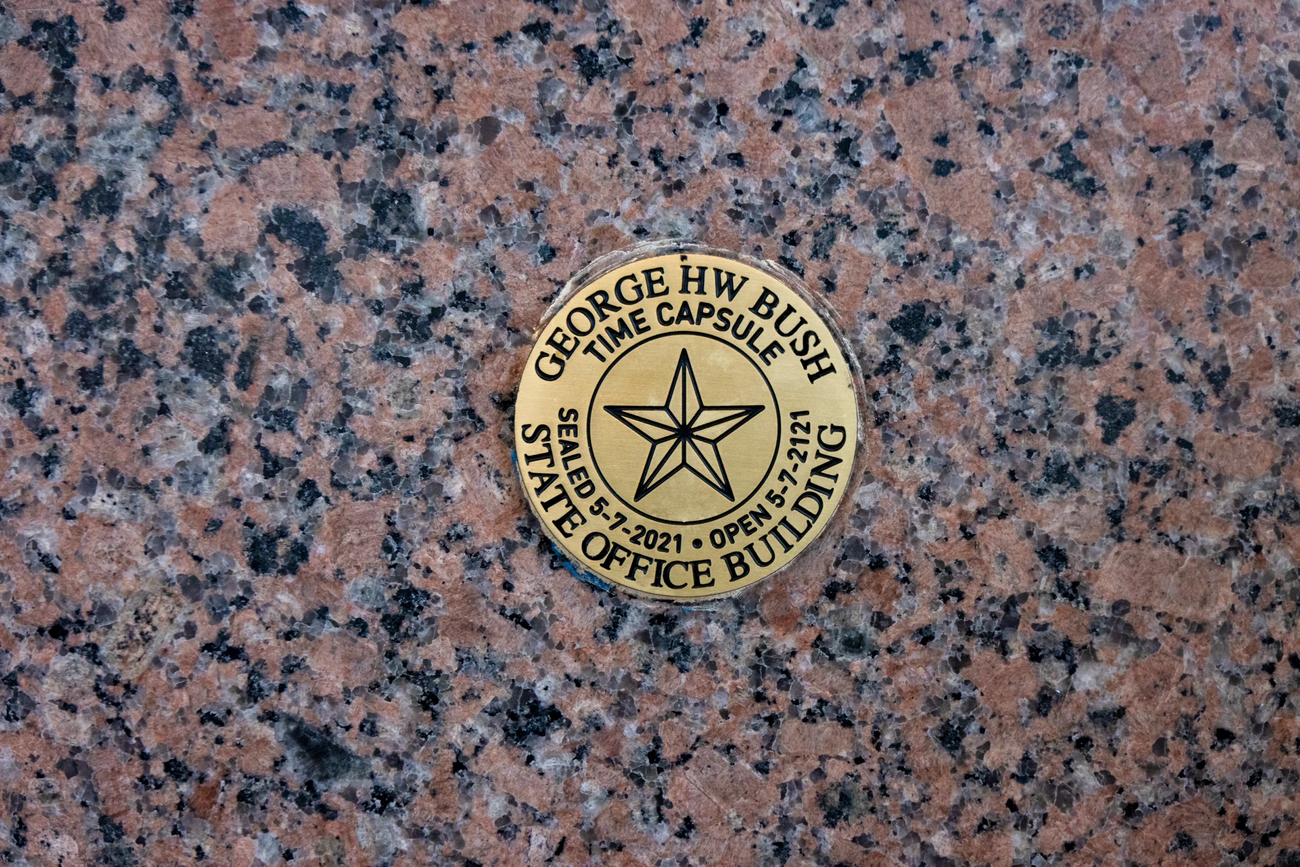Bronze plaque embedded in pink granite reads "George HW Bush Time Capsule." Features a star and dates: Sealed 5/7/2021, Open 5/2/2171.