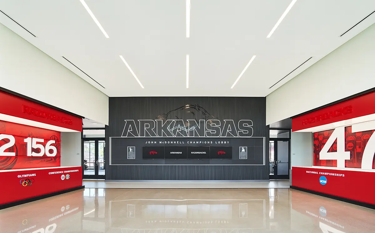 Spacious lobby with a modern design, featuring bold "Arkansas" text and championship numbers. Red accents and sleek lines create an inspiring atmosphere.