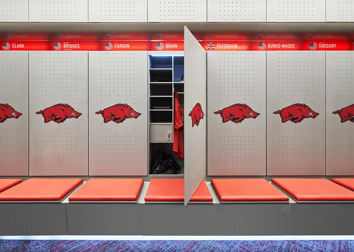 A man walks down a modern hallway with a large, backlit "ARKANSAS" sign on the wall. The design is sleek and bright, conveying a sense of innovation.