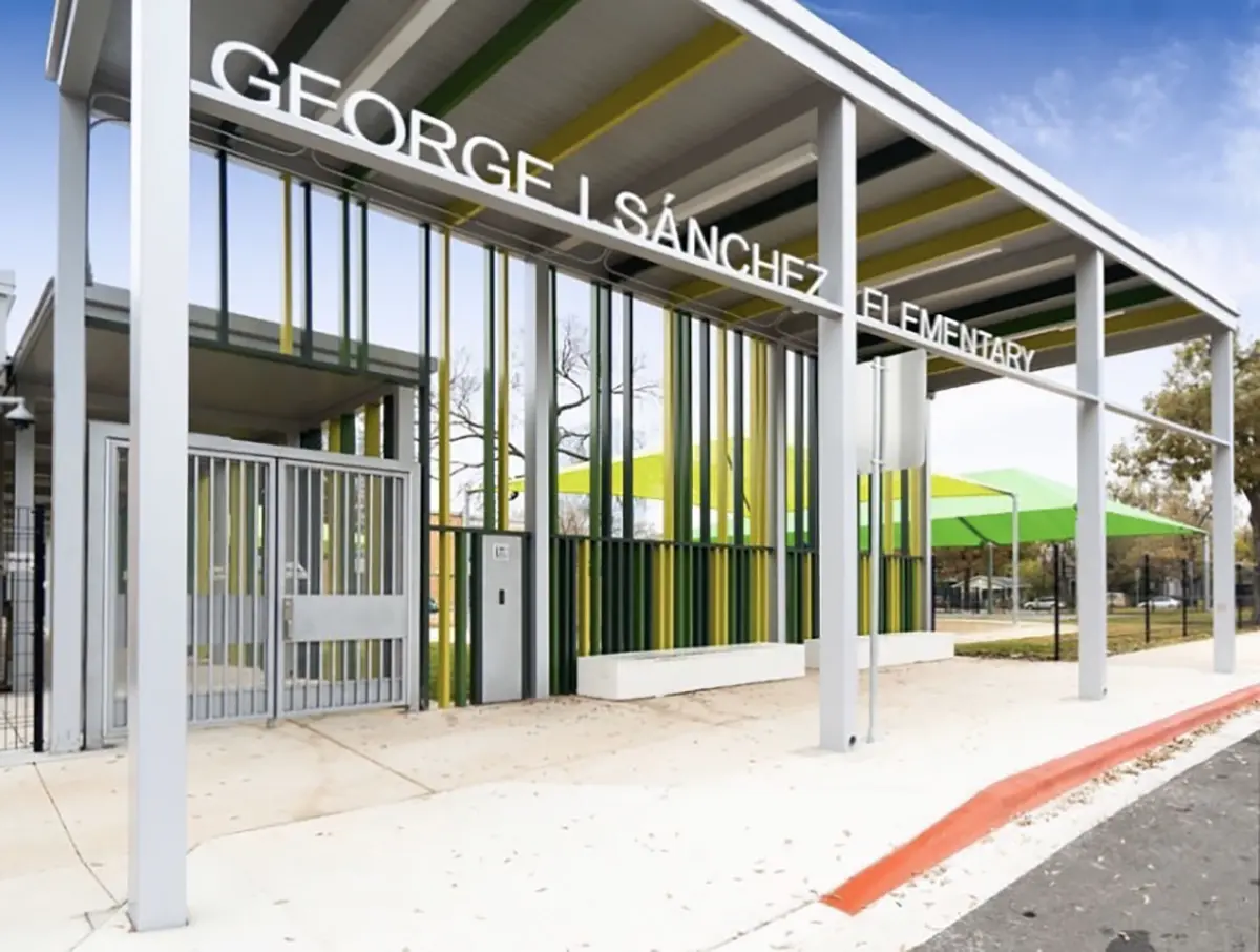 Modern entrance of George I. Sánchez Elementary School, featuring sleek metal and glass design with vertical colored panels and green shade structures.