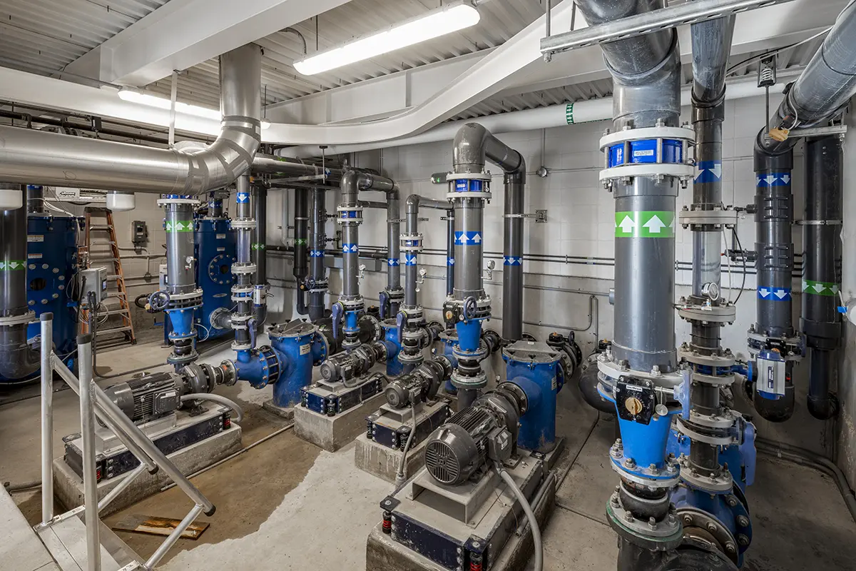 여러 개의 파란색 펌프와 회색 파이프가 있는 산업용 공간으로, 유체 제어를 나타냅니다. 밝은 조명과 깔끔한 설정이 질서 정연한 느낌을 전달합니다.