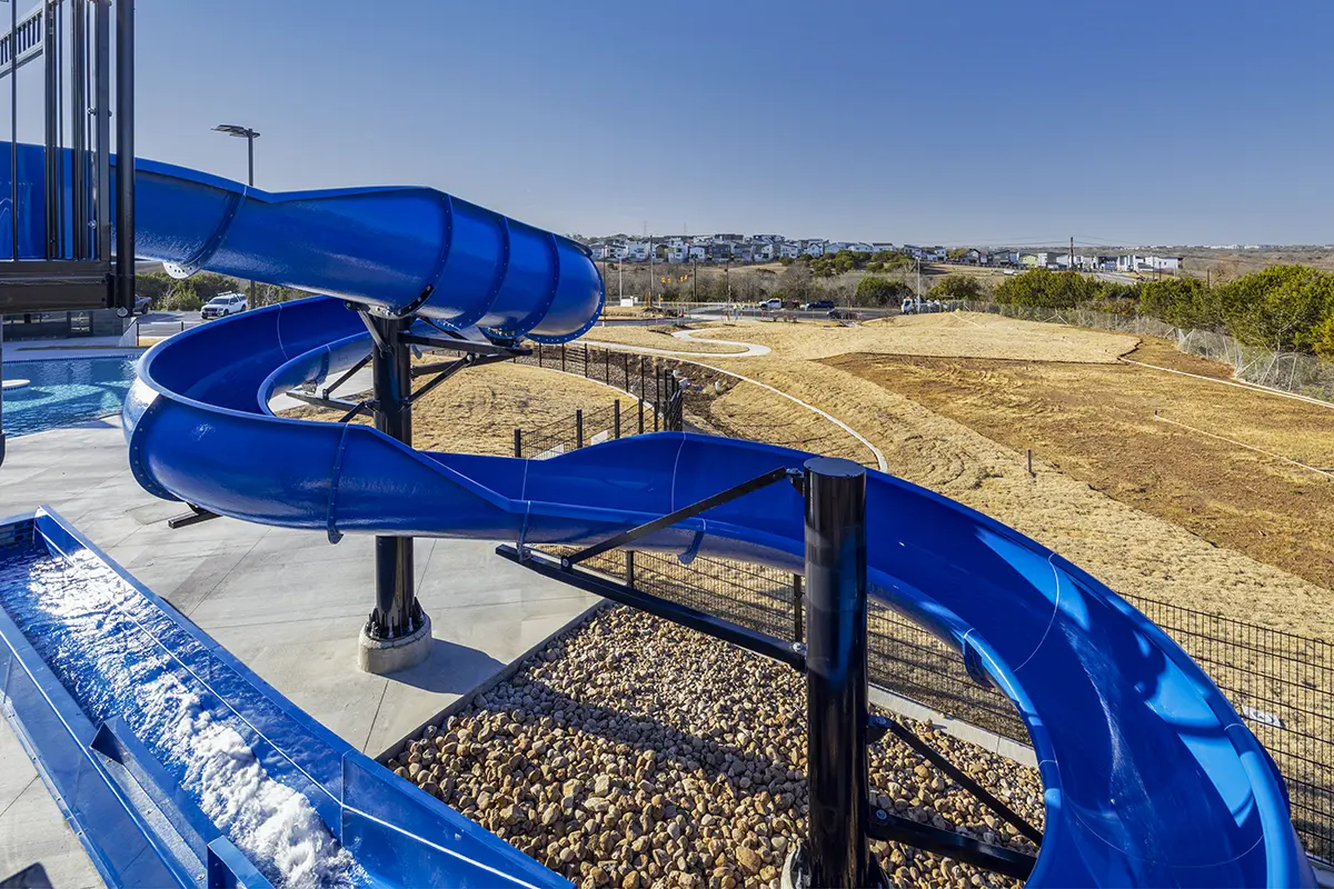 푸른 물길이 휘어져 내려가 수영장으로 이어지고, 그 주변에는 돌길과 푸른 잔디밭이 펼쳐져 있다. 맑고 푸른 하늘 아래, 그 풍경은 밝고 매력적이다.