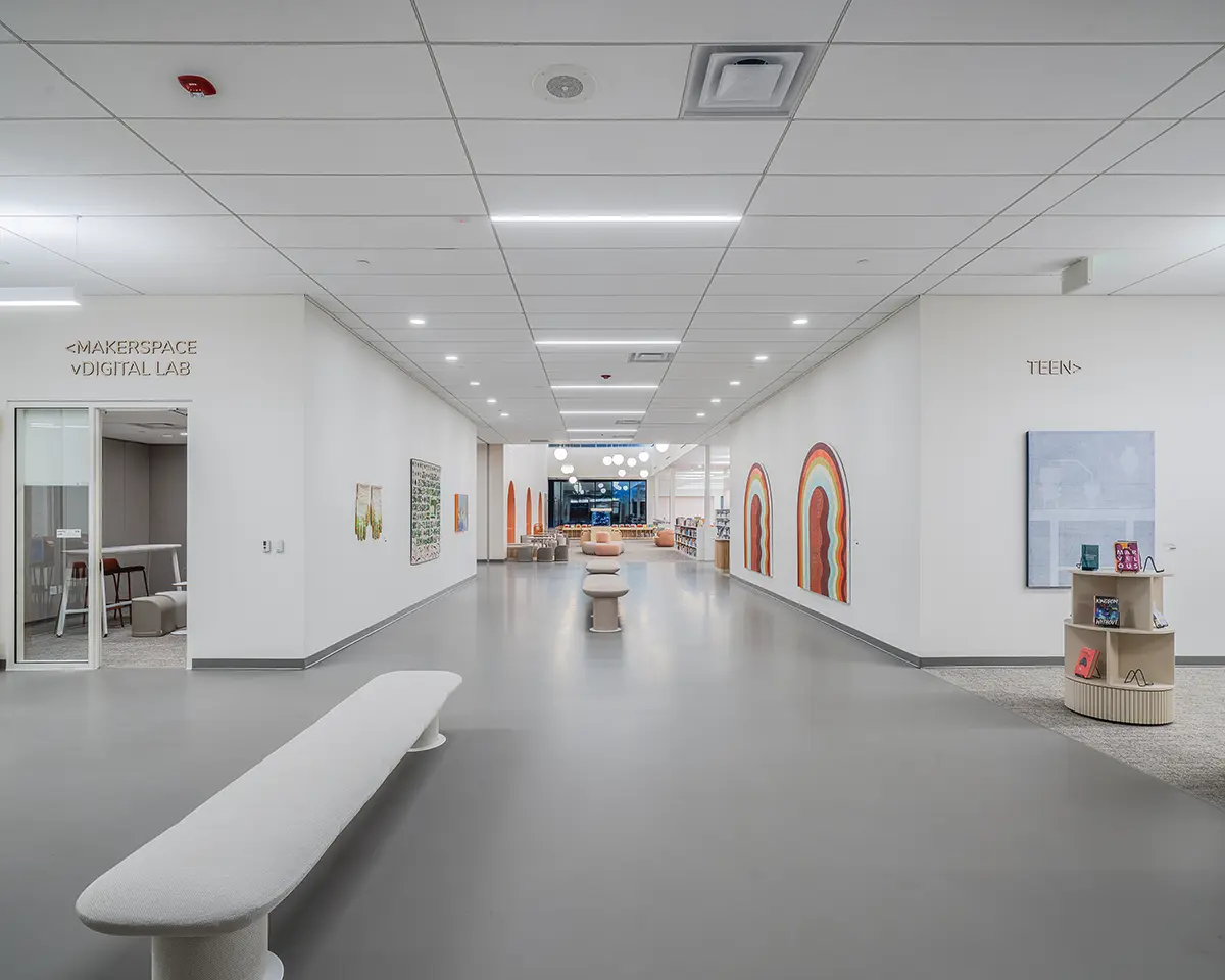 Modern library interior with white walls and gray flooring. Bright murals adorn one side, and the "Makerspace Digital Lab" and "Teen" areas are visible.
