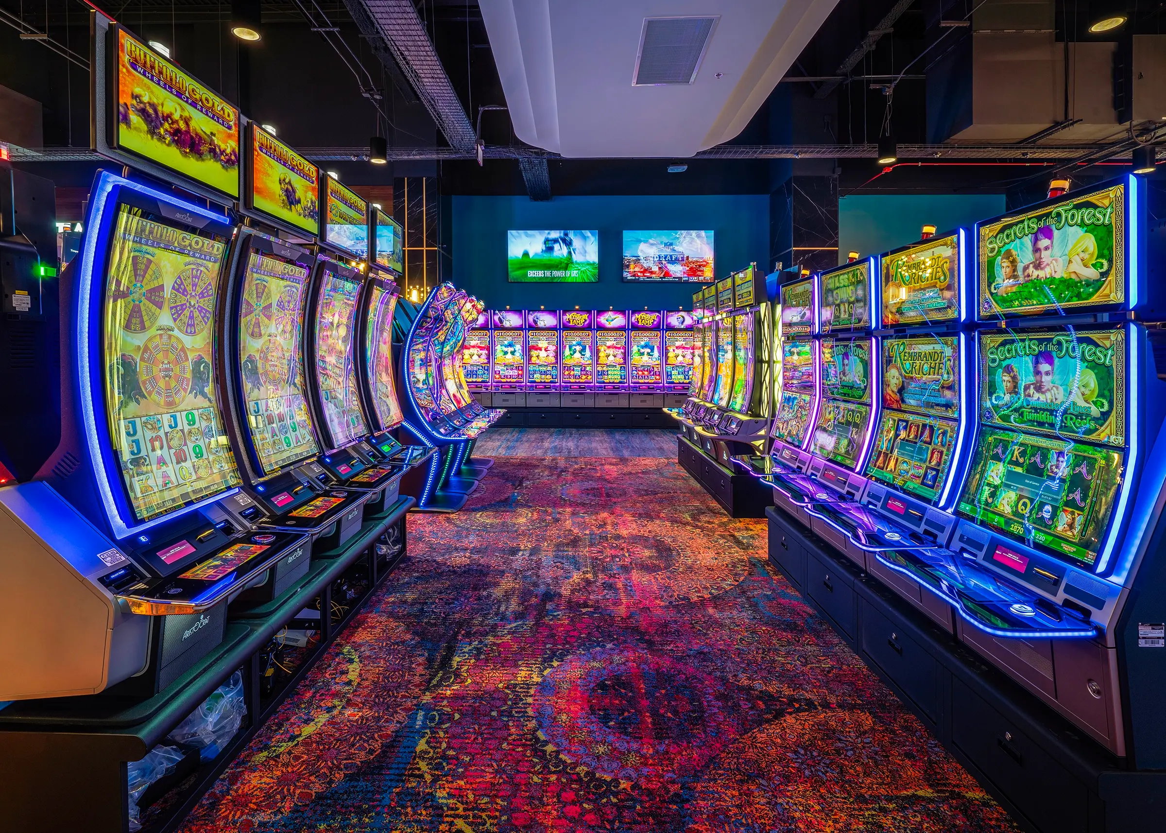 Una animada sala de juegos con hileras de máquinas tragaperras sobre una colorida moqueta. Las luces de neón iluminan las máquinas, creando un ambiente emocionante y dinámico.