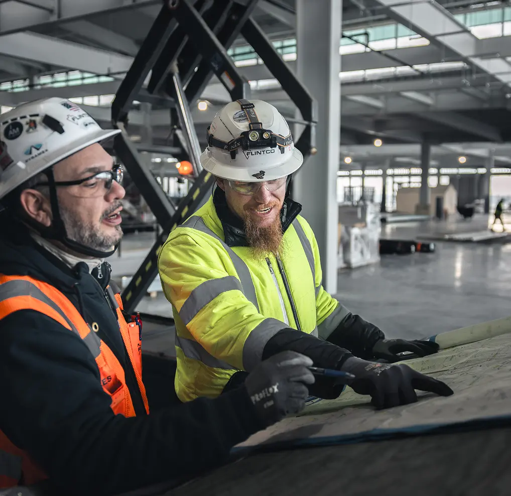 Workers in orange and yellow vests with hard hats