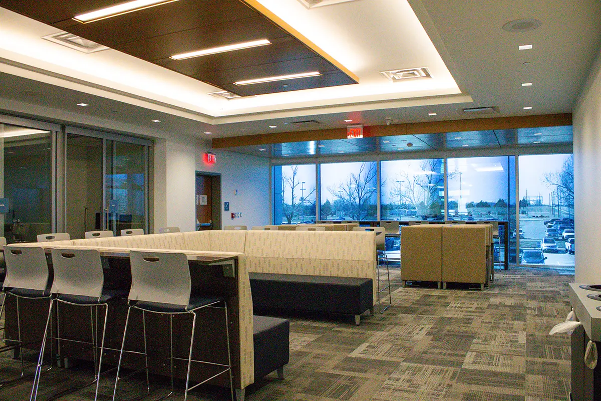 Modern meeting space with sleek tables, high chairs, and couches. Large windows reveal a snowy landscape, creating a serene, professional atmosphere.