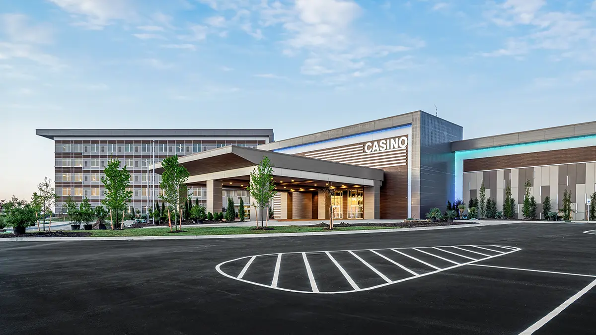 Casino interior with colorful carpet and modern chandeliers. Slot machines flank the path leading to the "Lakeside Grill," where TVs line the wall.
