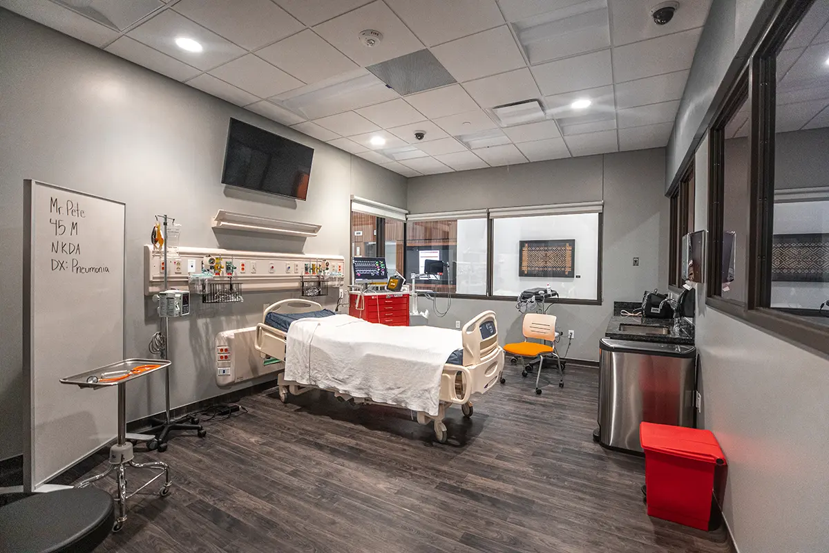 Hospital room with single bed, clean linens, and medical equipment. Notes on whiteboard read. Cozy yet clinical.